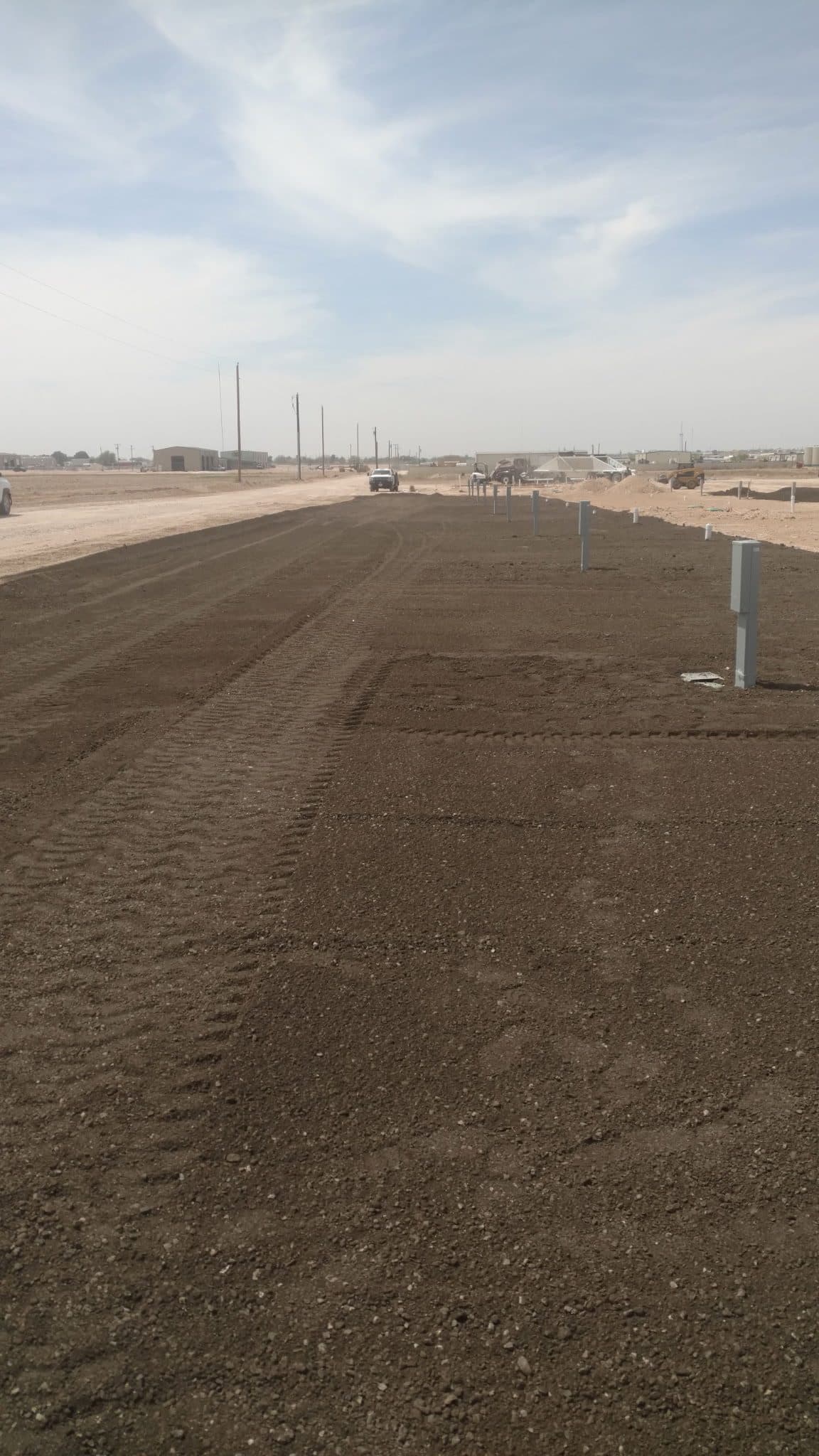 Freshly graded ranch road stretching toward the horizon across West Texas rangeland