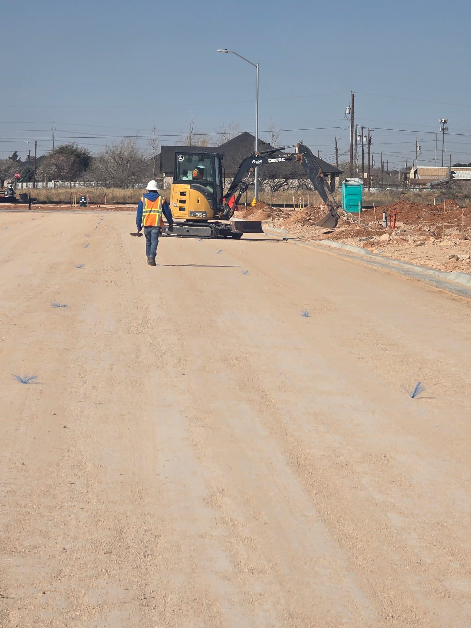 Rangefinder Excavation crew member walking alongside equipment on a subdivision street project